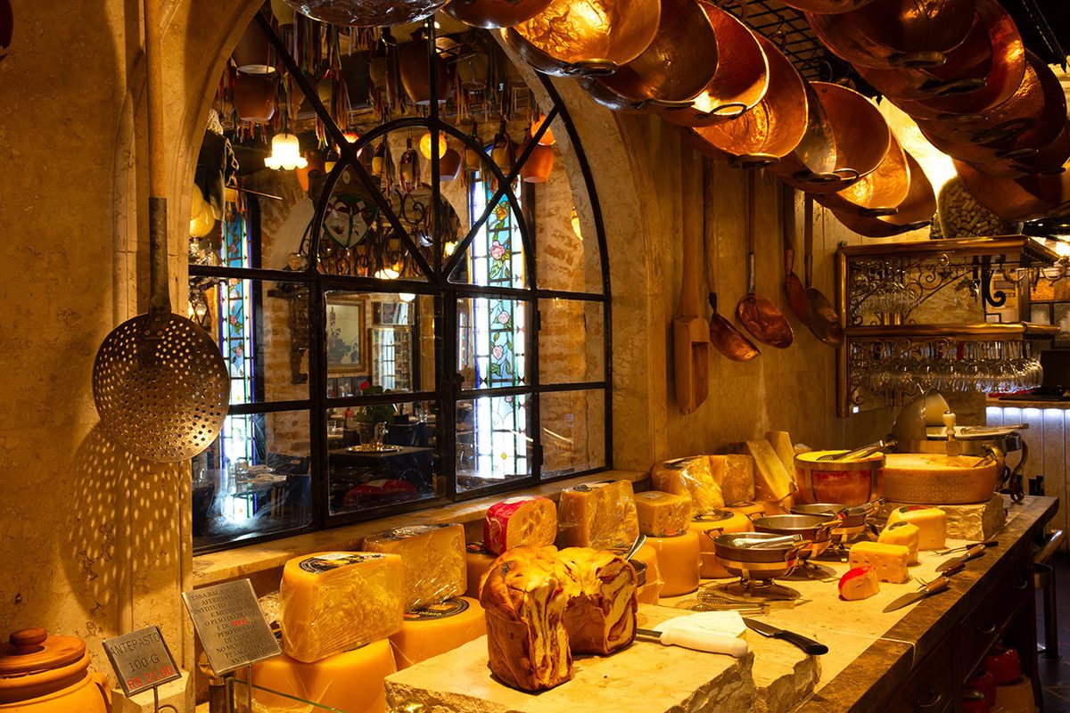 Sala de antepastos da Famiglia Mancini Trattoria, com panelas de cobre e queijos